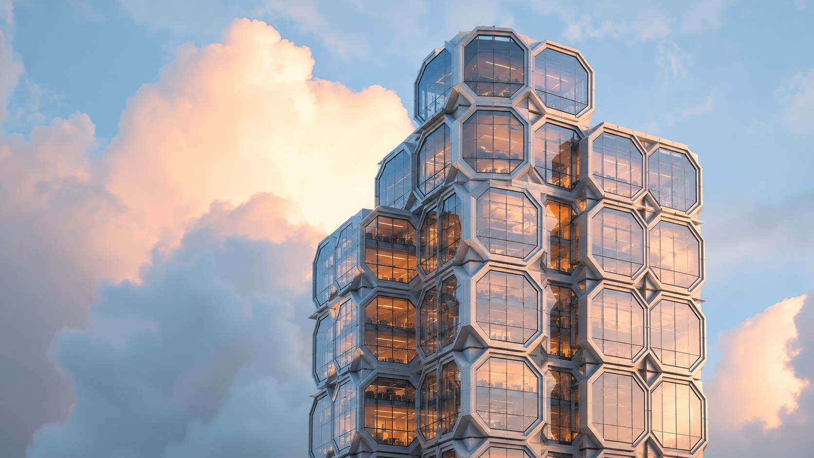 The crown of a tower built from stacked hexagonal glass cells, its interiors glowing warm at sunset